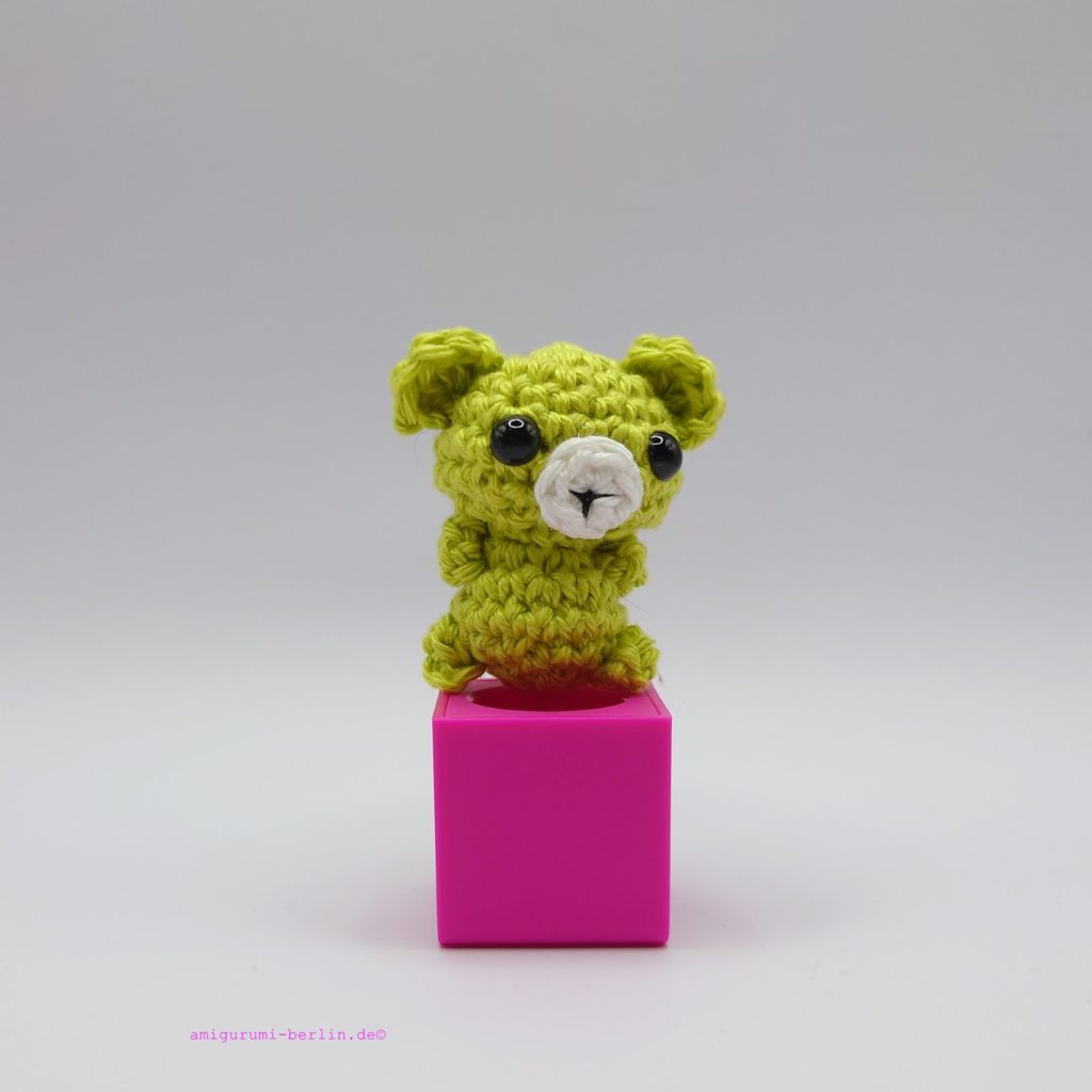 ein anisfarbener gehäkelter Bär auf einem pinkfarbenen Block an aniseed-colored crocheted bear on a pink block