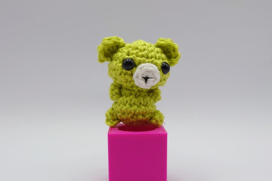 ein anisfarbener gehäkelter Bär auf einem pinkfarbenen Block an aniseed-colored crocheted bear on a pink block