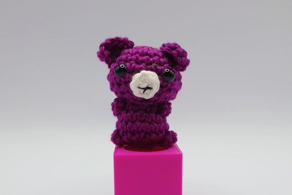 ein phloxfarbener gehäkelter Bär auf einem pinkfarbenen Block - a phlox-colored crocheted bear on a pink block